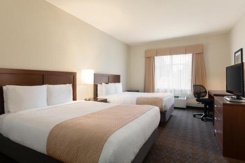 オタワにあるDays Inn by Wyndham Ottawa Airportのベッド2台、薄型テレビが備わるホテルルームです。