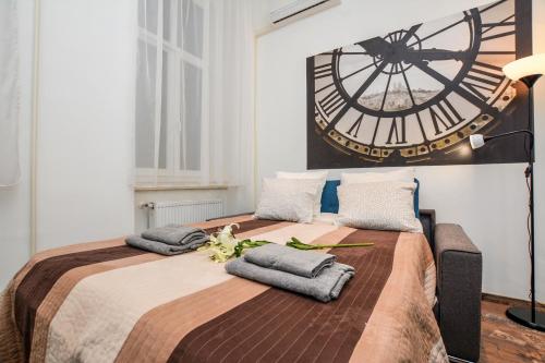 a large bed with towels on it with a clock on the wall at Timeless Apartment with FREE Private PARKING in Budapest