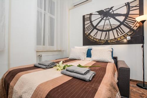ブダペストにあるTimeless Apartment with FREE Private PARKINGの大型ベッド(タオル付)、壁掛け時計が備わります。