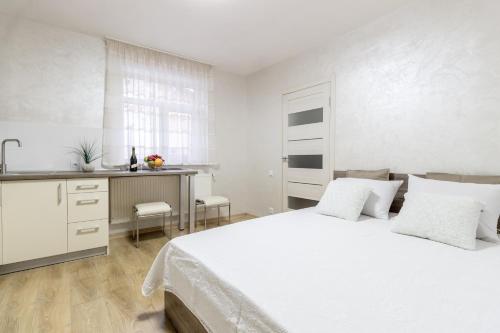 リヴィウにあるCity Center VIP studio apartmentの白いベッドルーム(ベッド1台付)、キッチンが備わります。