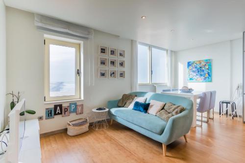 Una sala de estar con un sofá azul y una mesa. en João Beach House, en Leça da Palmeira