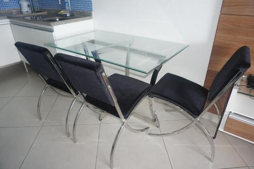 a glass table with four black chairs around it at Landscape Residence by Escala Imóveis in Fortaleza