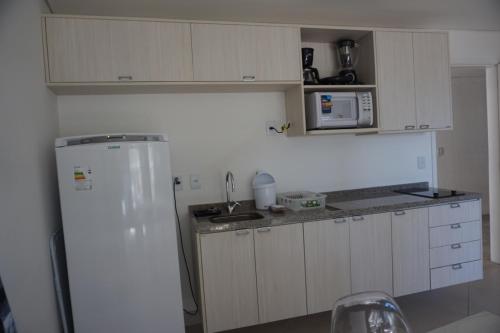a kitchen with white cabinets and a white refrigerator at Landscape Residence by Escala Imóveis in Fortaleza