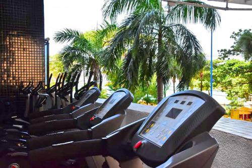 a row of exercise bikes in a gym with palm trees at Landscape Residence by Escala Imóveis in Fortaleza