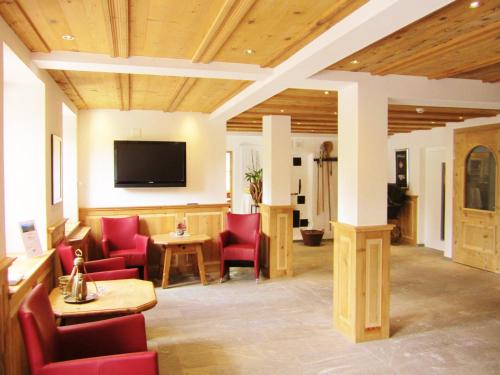 une salle d'attente avec des chaises rouges et une télévision à écran plat dans l'établissement Hotel Kistenpass, à Brigels
