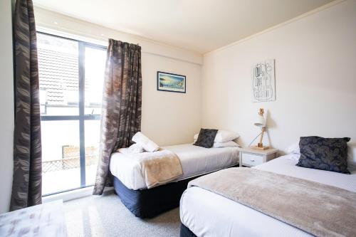 a bedroom with two beds and a window at Capri on Pilot Bay in Mount Maunganui