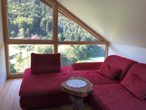 a living room with a red couch and a large window at Ferienwohnung HOF in Mühlenbach