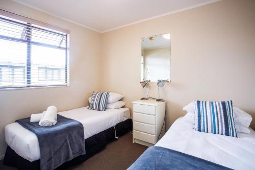 a bedroom with two beds and a mirror at Capri on Pilot Bay in Mount Maunganui