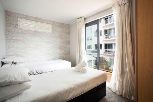 a bedroom with two beds and a large window at Capri on Pilot Bay in Mount Maunganui