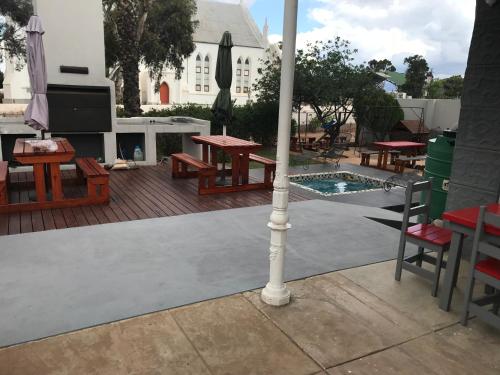 a patio with tables and benches and an umbrella at Towerzicht Guest House in Ladismith