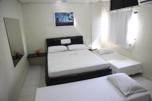 a room with two beds and a mirror at Hotel Piramide Pituba - Rua Pernambuco in Salvador