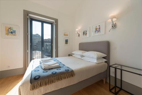 1 dormitorio con cama y ventana grande en Bom-Jardim Trindade, en Oporto
