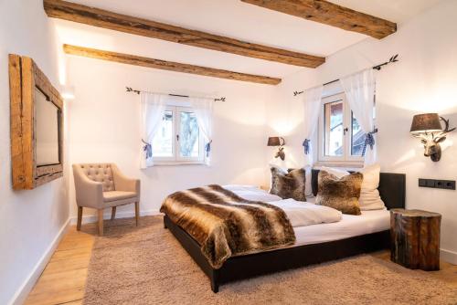 Schlafzimmer mit einem Bett, einem Stuhl und Fenstern in der Unterkunft Exklusives Alpenchalet in Bayrischzell