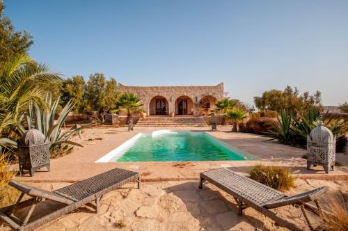 einen Pool mit zwei Stühlen und ein Haus in der Unterkunft Dar ZINZIN in Essaouira