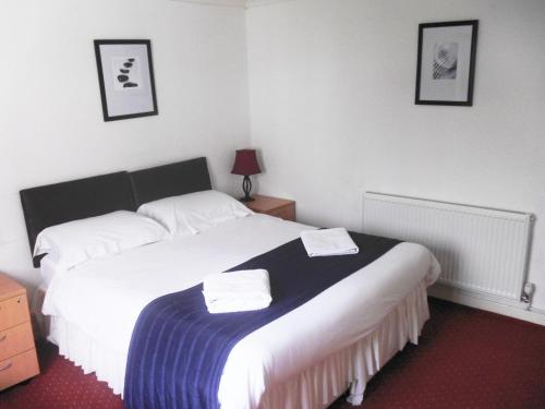 a bed room with a white bedspread and pillows at The Riverside Hotel in Monmouth
