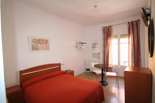 1 dormitorio con cama, mesa y ventana en Hostal Juventus, en Portbou