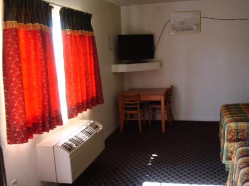 a room with a bed and a television and a window at American Inn in South El Monte