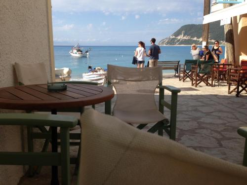 a table and chairs on a beach with a boat in the water at Konstantina Studios in Agios Nikitas