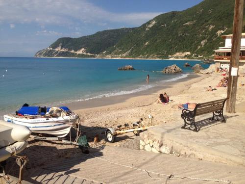 a boat parked on a beach next to a bench at Konstantina Studios in Agios Nikitas