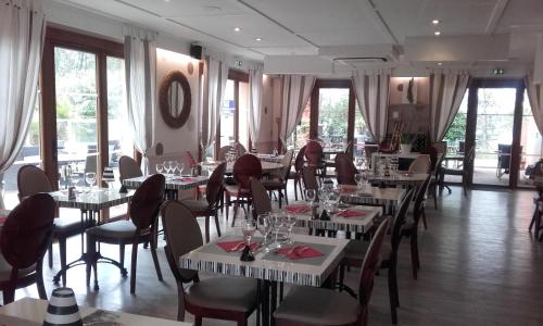 a restaurant with white tables and chairs and windows at Kyriad Montpellier Nord Parc Euromédecine in Saint-Clément-de-Rivière