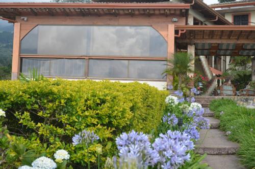 a garden with flowers in front of a house at Finca Paraiso Mountain Retreat near San Jose Airport in Birrí