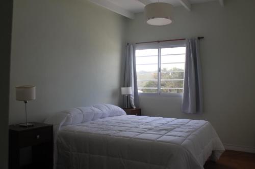 1 dormitorio con cama blanca y ventana en ELARCO Complejo de Mar en San Clemente del Tuyú