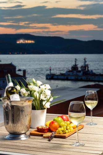 a table with two glasses of white wine and fruit at Artur Hotel in Canakkale