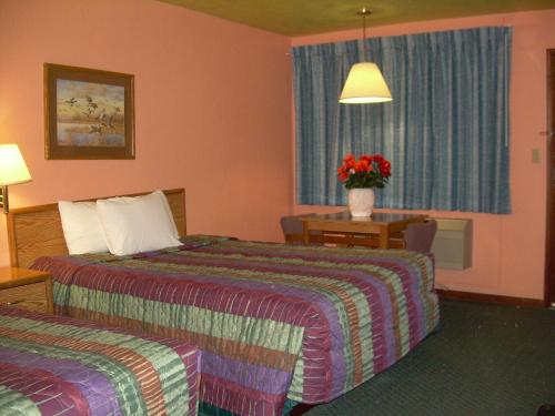 una camera d'albergo con due letti e un vaso di fiori di 83 motel a North Platte