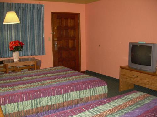 Una habitación de hotel con dos camas y un televisor. en 83 motel, en North Platte