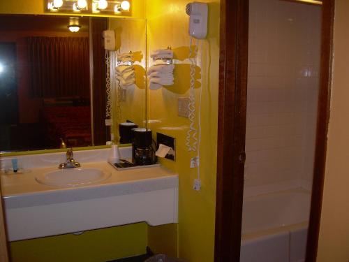 Un baño con lavabo, espejo y bañera. en 83 motel, en North Platte