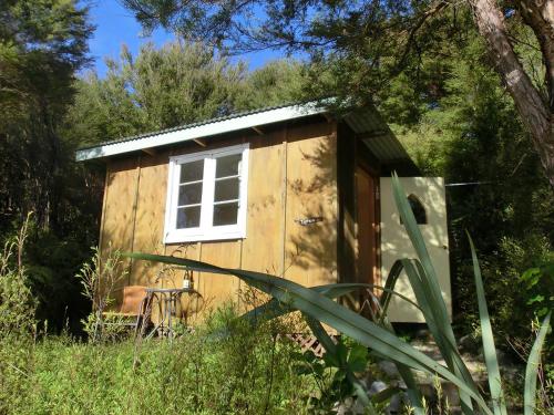 a small shed with a window in a field at Ao Marama Retreat in Collingwood