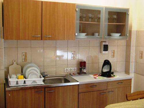 a kitchen with wooden cabinets and a sink with dishes at Amber Apartments in Palanga
