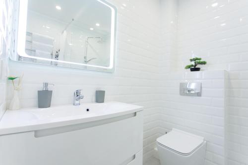 a white bathroom with a sink and a toilet at Apart-Hotel "LAVINA" in Sumy