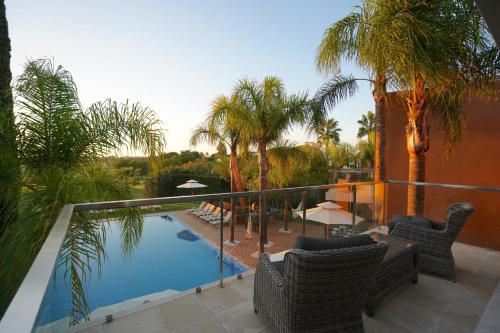 a balcony with chairs and a swimming pool with palm trees at Villa Laguna Golf-Frente ao laguna Golf in Vilamoura