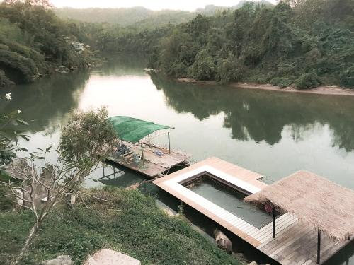a river with a pier and a boat in the water at Kwainoy Riverpark in Sai Yok