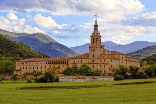 un gran edificio con una torre de reloj en un campo en CASA TURÍSTICA Villa Carmen, CON AMPLIO JARDIN QUE INCLUYE BARBACOA, 2 PORCHES, PARKING PRIVADO Y PISCINA, en Arenzana de Abajo