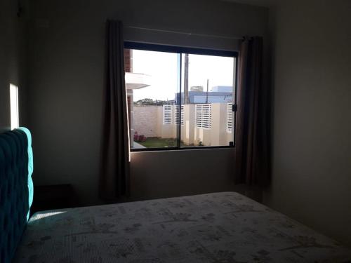 a bedroom with a bed and a window at Residencial Franca Garopaba in Garopaba