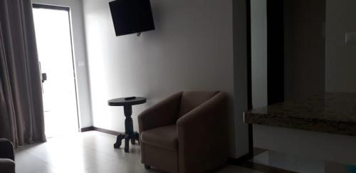 a living room with a chair and a table at Residencial Franca Garopaba in Garopaba