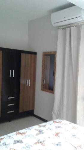 a bedroom with a bed and wooden cabinets and a window at Residencial Franca Garopaba in Garopaba