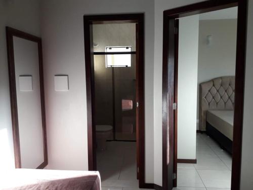 a room with two mirrors and a door with a bed at Residencial Franca Garopaba in Garopaba