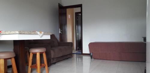 a living room with a couch and a table and stools at Residencial Franca Garopaba in Garopaba