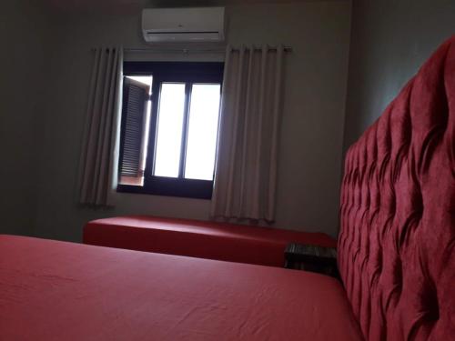 a bedroom with a red bed and a window at Residencial Franca Garopaba in Garopaba