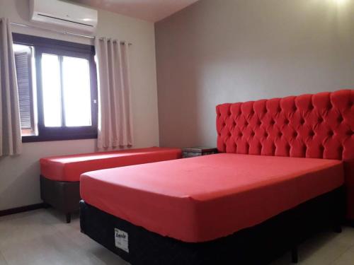 a bedroom with two red beds and a window at Residencial Franca Garopaba in Garopaba