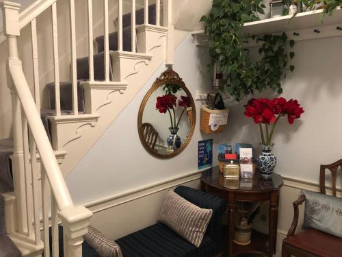 a stairway with a mirror and flowers on the wall at Northey Street House in Salem