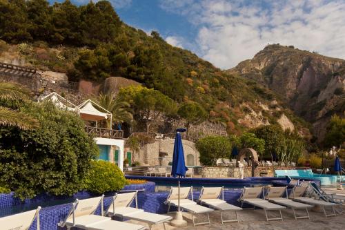 a group of chairs and a pool with a mountain at Apollon Club & Thermal Spa in Ischia