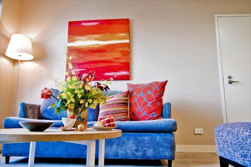 a living room with a blue couch and a painting at Quest Mascot in Sydney