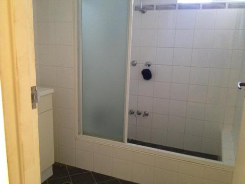 Un baño con ducha con puerta de cristal. en Airport budget room, en Perth