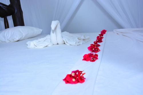a white bed with red flowers on it at Randu Homestay and Restaurant in Tangalle