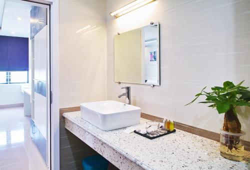 une salle de bain blanche avec un lavabo et un miroir dans l'établissement Thiên An Hotel, à Hai Phong