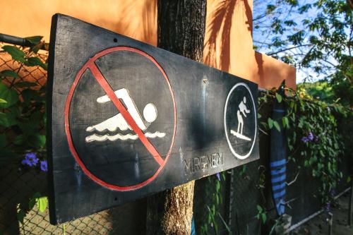 a sign on a tree with a no smoking sign at Pipe House Playa Grande in Playa Grande